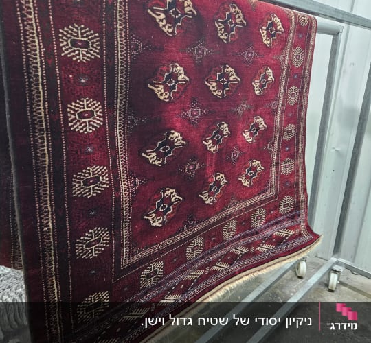 שטיח אדום תלוי על מתקן מתכת לניקוי
